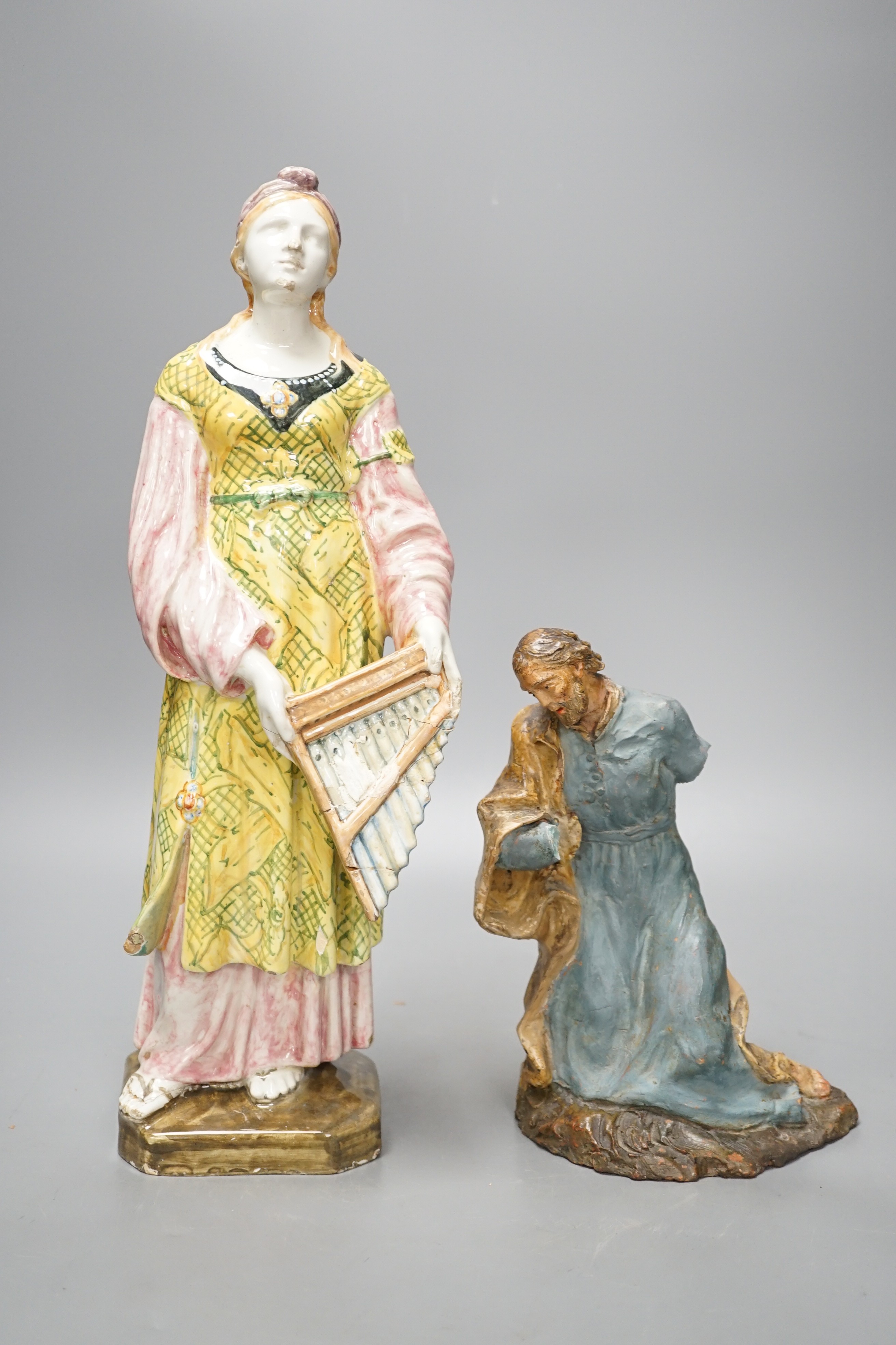 A late 19th century Italian maiolica figure of a Grecian woman or goddess with pipes and Sicilian terracotta figure of a Saint, tallest 38cm